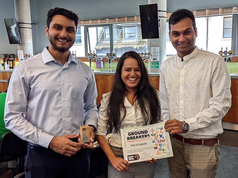 Three smiling people holding Groundbreakers Award certificate